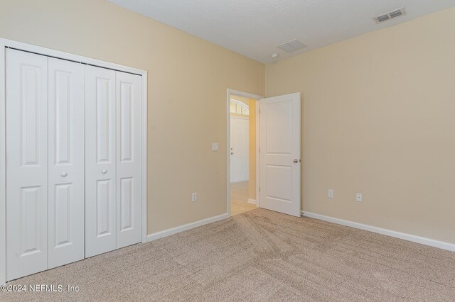 unfurnished bedroom with a closet and light colored carpet