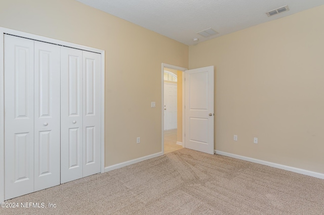 unfurnished bedroom featuring light colored carpet and a closet