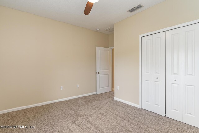 unfurnished bedroom featuring ceiling fan, carpet flooring, and a closet