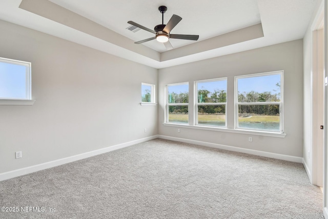 carpeted spare room featuring a raised ceiling and ceiling fan