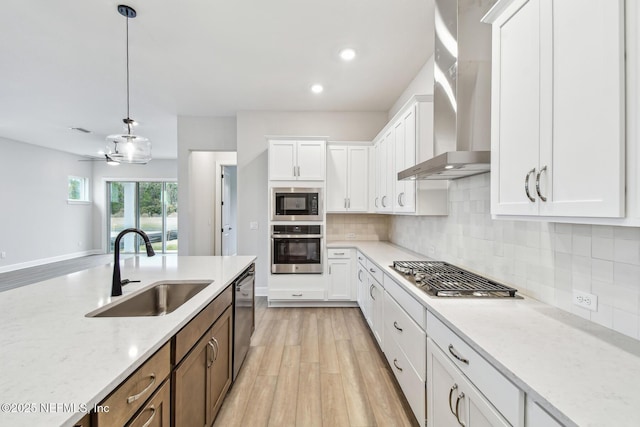 kitchen featuring stainless steel appliances, sink, wall chimney range hood, and white cabinets