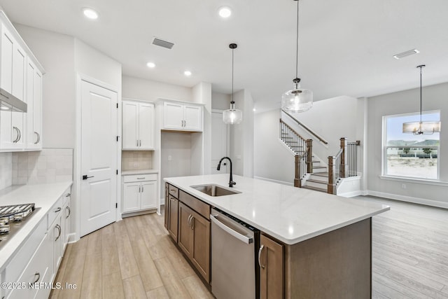 kitchen with decorative light fixtures, white cabinetry, sink, decorative backsplash, and stainless steel appliances