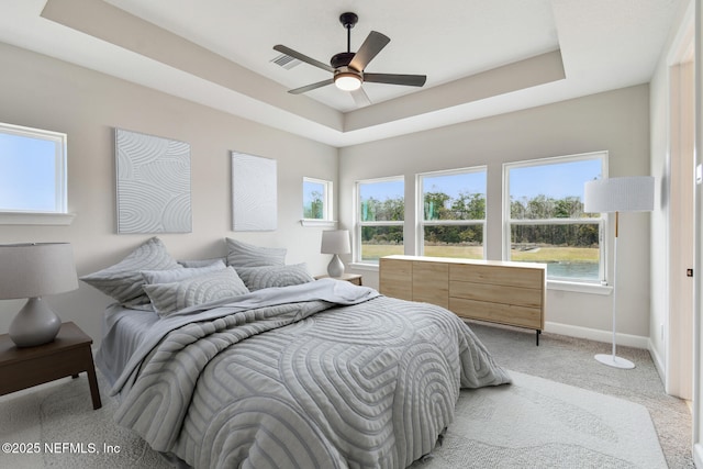 carpeted bedroom featuring a tray ceiling and ceiling fan