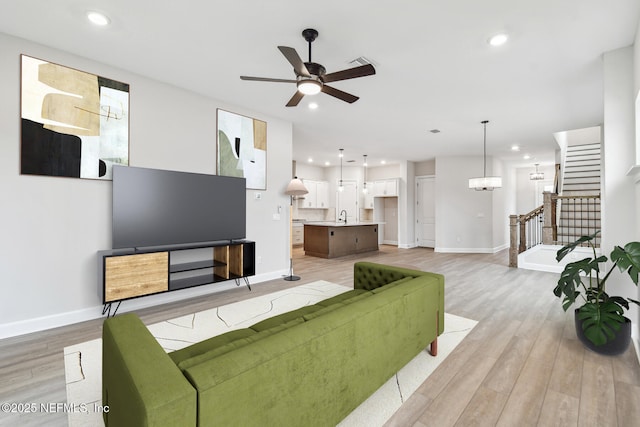 living room with sink, light hardwood / wood-style floors, and ceiling fan