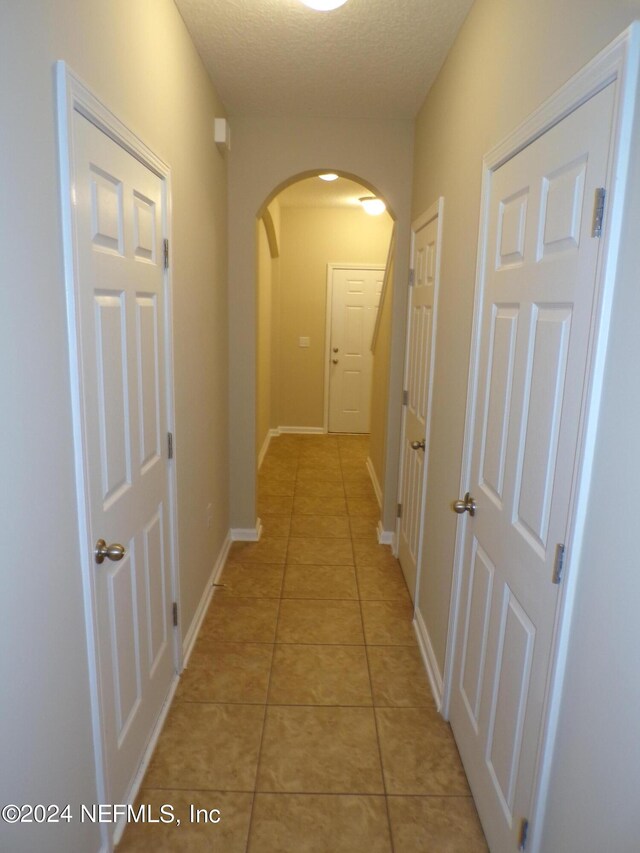 corridor with a textured ceiling and light tile patterned floors