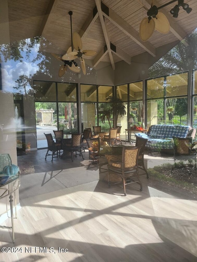 sunroom / solarium with ceiling fan, wood ceiling, and vaulted ceiling with beams