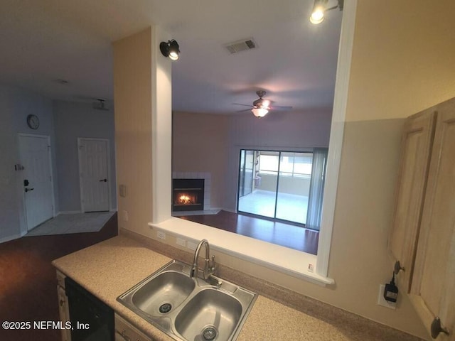 kitchen featuring ceiling fan, a fireplace, and sink