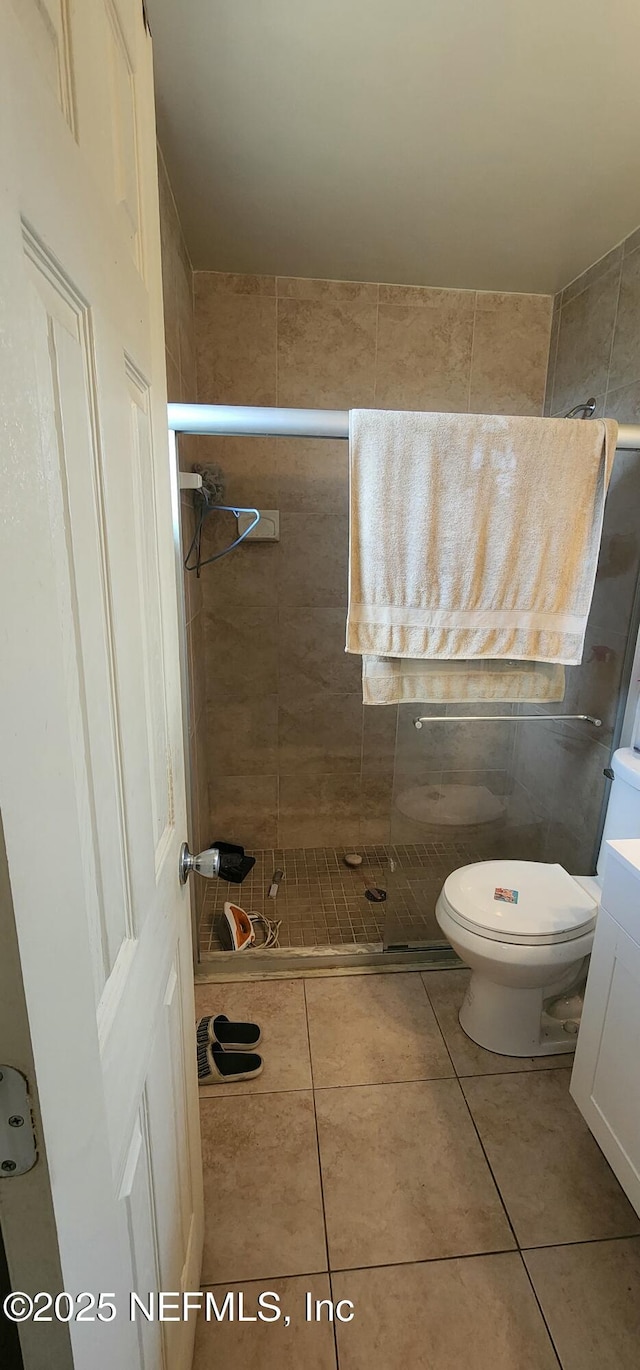 bathroom featuring tile patterned flooring, vanity, a tile shower, and toilet