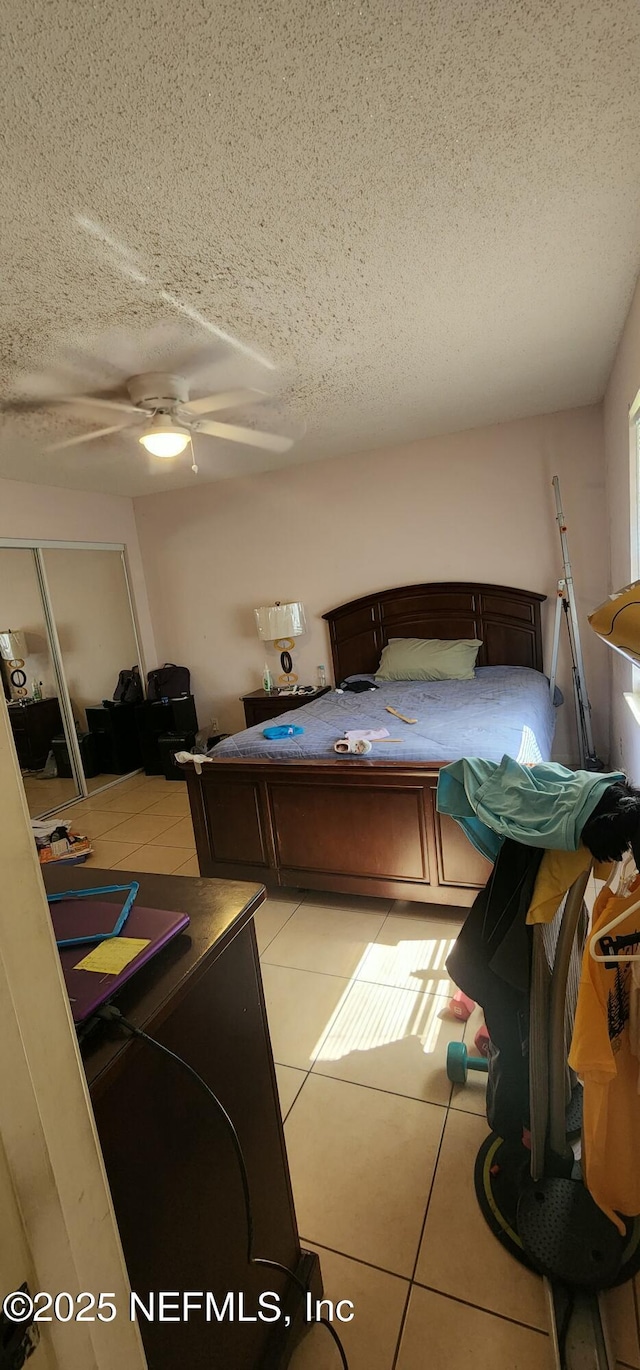 tiled bedroom featuring ceiling fan and a textured ceiling