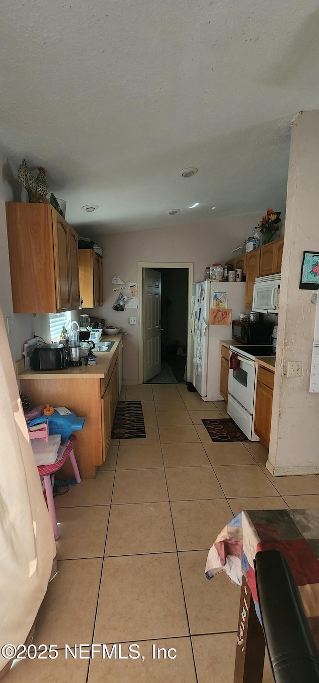 kitchen with white appliances and light tile patterned flooring