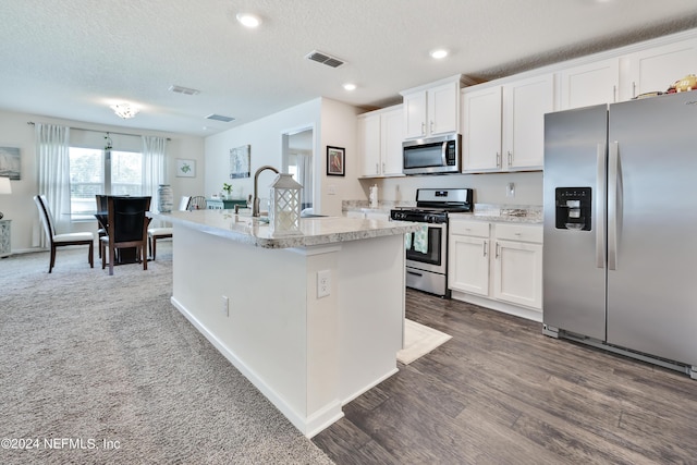 kitchen with stainless steel appliances, a kitchen island with sink, light countertops, and white cabinetry