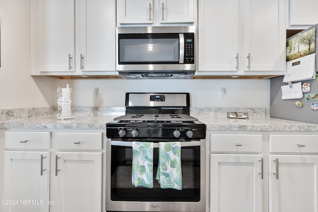 kitchen featuring white cabinetry, stainless steel appliances, and light stone countertops