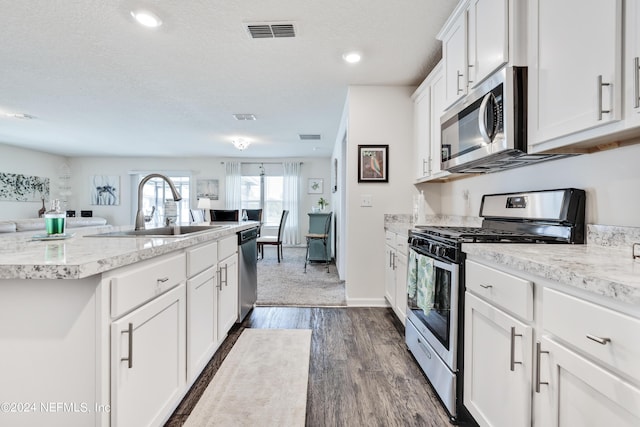 kitchen with visible vents, white cabinets, appliances with stainless steel finishes, dark wood-type flooring, and a sink