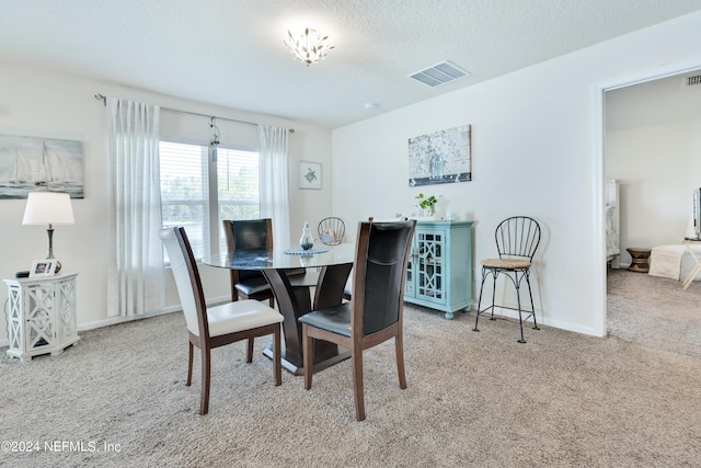 dining space with baseboards, visible vents, a textured ceiling, and light colored carpet