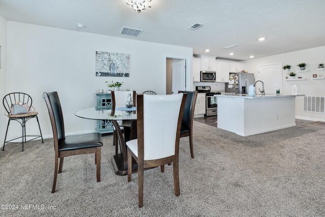 dining space featuring sink and light colored carpet