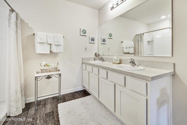 bathroom with double sink vanity, a textured ceiling, and wood-type flooring