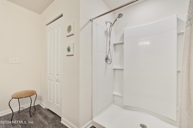 full bathroom with wood finished floors, a shower stall, and baseboards