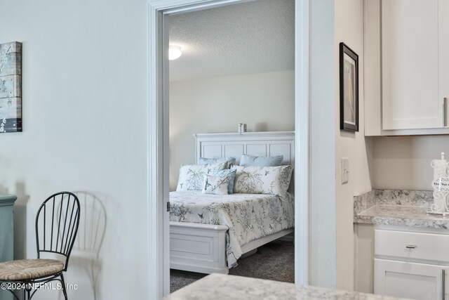 bedroom featuring a textured ceiling and dark carpet