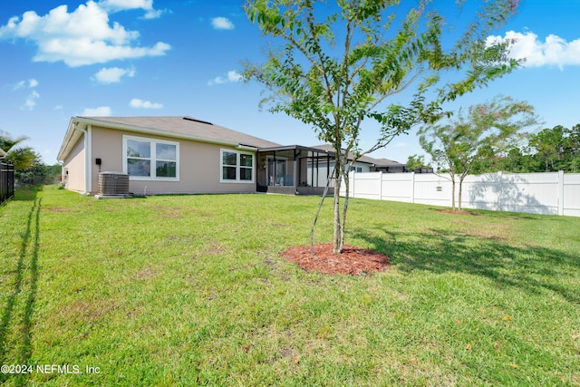 rear view of property with central air condition unit, a fenced backyard, a lawn, and stucco siding