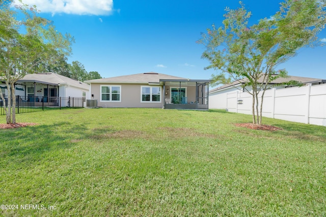 rear view of house featuring a sunroom, a fenced backyard, stucco siding, and a yard