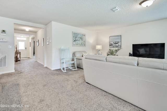 living room with light colored carpet, visible vents, a textured ceiling, and baseboards