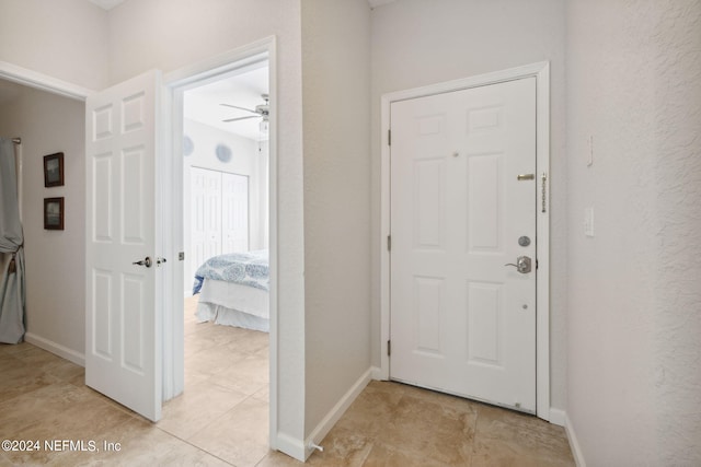 foyer featuring baseboards, a ceiling fan, and a textured wall