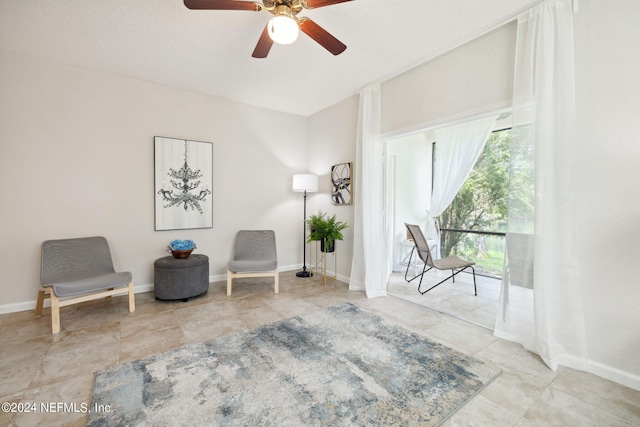 living area with ceiling fan and baseboards