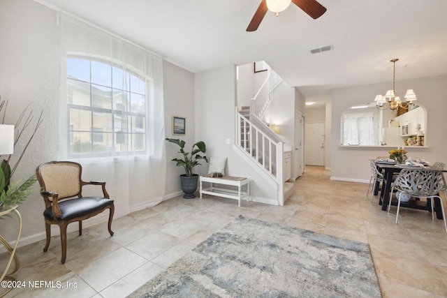 living area with baseboards, stairway, visible vents, and a healthy amount of sunlight