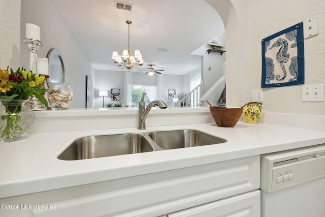 kitchen featuring visible vents, hanging light fixtures, white dishwasher, light countertops, and a sink