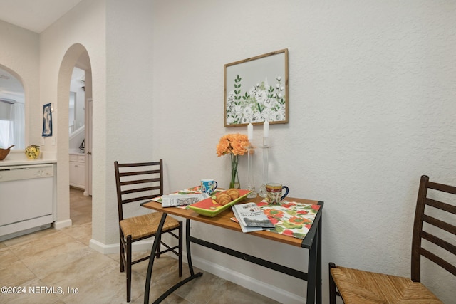 dining area with light tile patterned floors, baseboards, arched walkways, and a textured wall