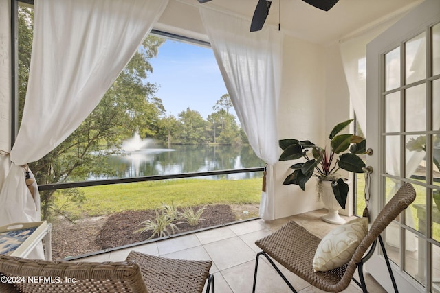 sunroom / solarium with a ceiling fan and a water view