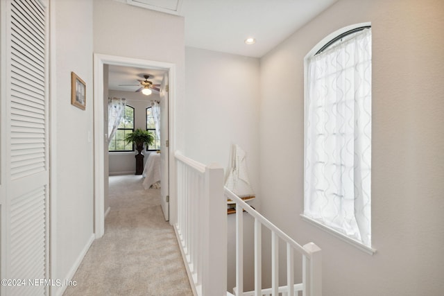 hall with recessed lighting, baseboards, light colored carpet, and an upstairs landing