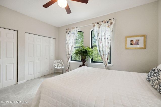 bedroom with multiple closets, light colored carpet, and ceiling fan