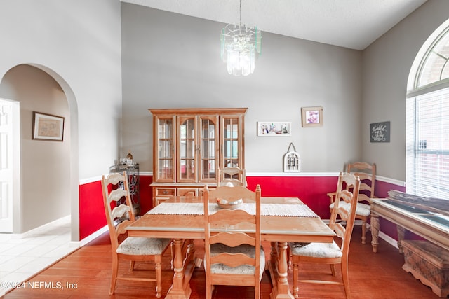 dining room featuring wood-type flooring, an inviting chandelier, and high vaulted ceiling