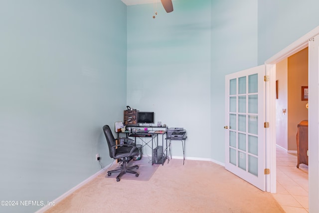 carpeted office with a high ceiling and ceiling fan