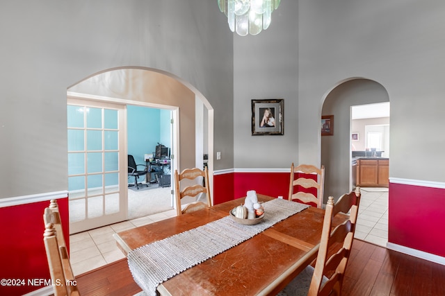 dining area with french doors, light wood-type flooring, and a high ceiling