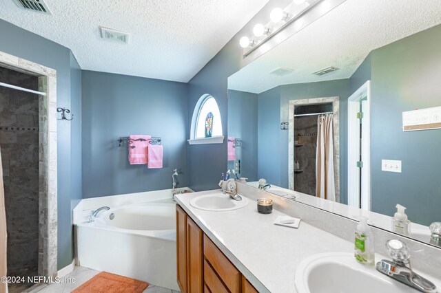 bathroom featuring vanity, a textured ceiling, plus walk in shower, and tile patterned floors