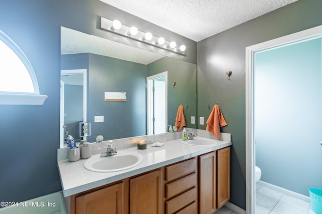 bathroom with tile patterned floors, a textured ceiling, vanity, and toilet