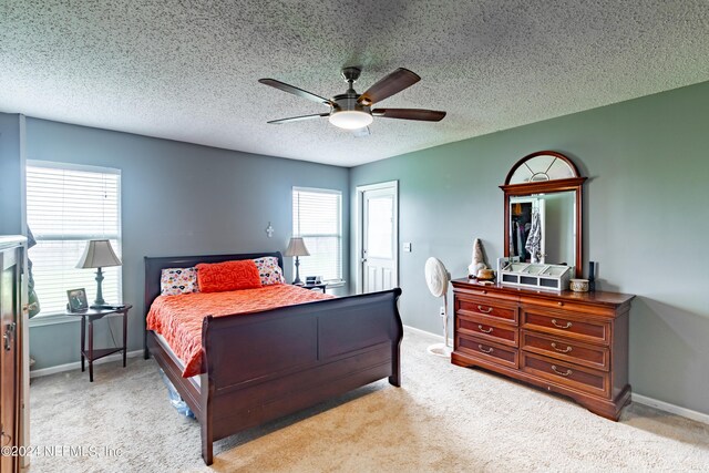 carpeted bedroom featuring multiple windows, ceiling fan, and a textured ceiling