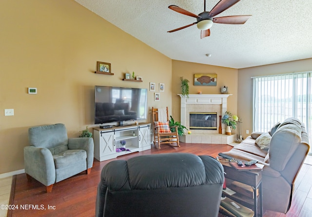 living room featuring a fireplace, a textured ceiling, lofted ceiling, ceiling fan, and hardwood / wood-style flooring