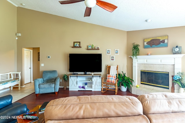 living room featuring ceiling fan, a textured ceiling, high vaulted ceiling, hardwood / wood-style flooring, and a fireplace