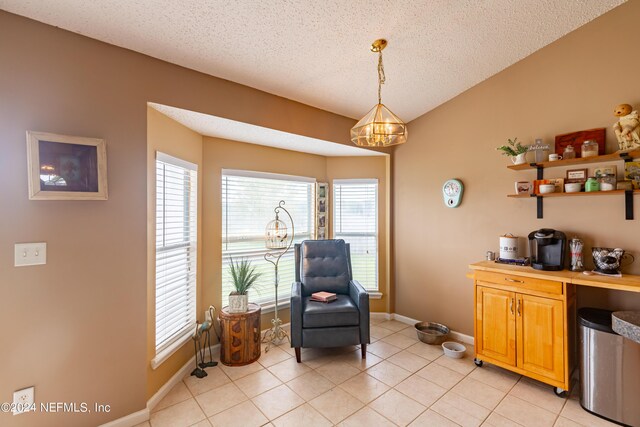 sitting room with a textured ceiling, light tile patterned floors, and a chandelier