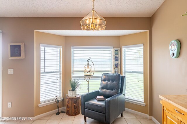 sitting room featuring a textured ceiling, light tile patterned floors, and a chandelier