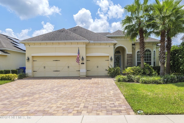 view of front of property featuring roof with shingles, decorative driveway, an attached garage, and stucco siding