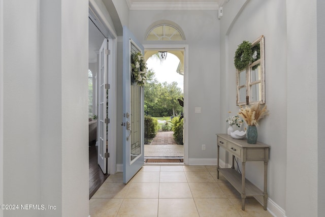 entrance foyer featuring light tile patterned floors, baseboards, and crown molding