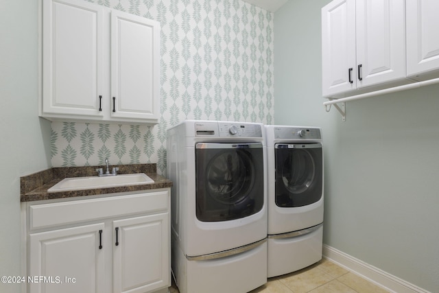 clothes washing area featuring light tile patterned floors, a sink, baseboards, cabinet space, and washing machine and clothes dryer