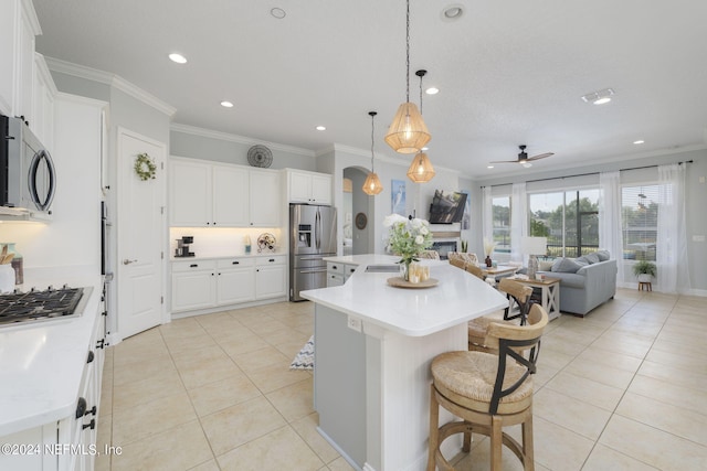 kitchen featuring light tile patterned floors, stainless steel appliances, a kitchen island, light countertops, and crown molding