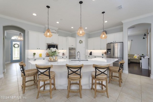 kitchen with appliances with stainless steel finishes, arched walkways, a sink, and ornamental molding