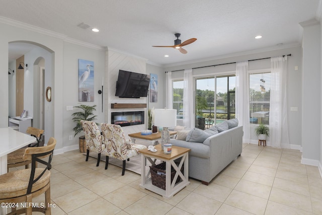 living area featuring a large fireplace, a healthy amount of sunlight, and crown molding