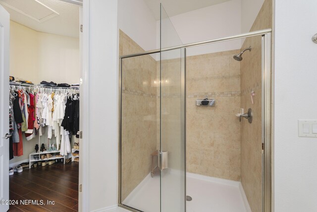 full bath with a shower stall, a spacious closet, and wood finished floors